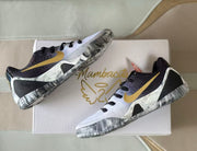 Angled overhead view of the sneakers placed on a white box with visible gold graphics.