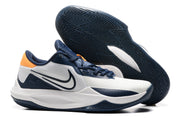 White and navy basketball shoe with orange heel accents.