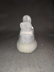 Front view of a silver-gray sneaker showing the rounded toe, knit upper, laces, and padded tongue.