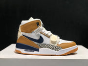 Side profile of one Jordan Legacy 312 sneaker showing the tan collar, navy Swoosh, elephant-print panel, and strap.