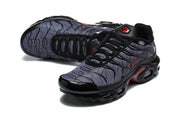 Angled top view of Nike Air Max Plus sneakers with patterned grey uppers.