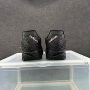 Rear view of the black sneakers showing the white “TWELVE” text on both heels.