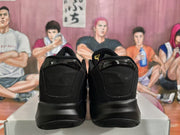 Rear view of the black sneakers showing the heel construction and glossy heel panels.