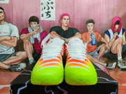 Front view of orange, neon green, and white Nike sneakers with white laces.