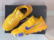Pair of yellow and purple low-top basketball sneakers displayed on a dark shoebox.