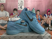 Angled side view of the blue basketball sneakers with dark Swoosh-style branding and Kobe-inspired hangtag details.