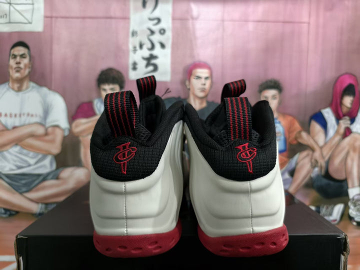 Rear view of white and red high-top basketball sneakers with black collars and red heel embroidery.