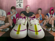 Front view of a pair of white Converse sneakers with purple and lime-green accents.