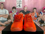 Front view of bright orange Nike Zoom basketball sneakers with red-orange laces and silver detailing.