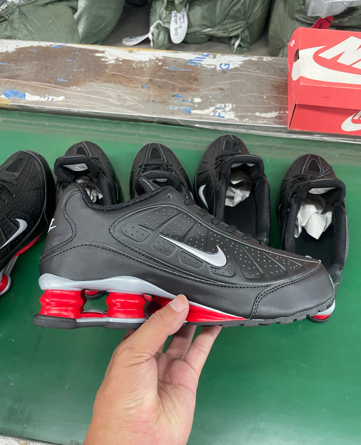 Black and dark gray Nike low-top sneaker with a white side Swoosh and red cushioning columns