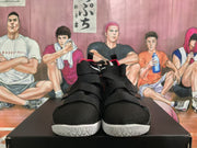 Front view showing the black textured uppers, layered straps, red interior accents, and white outsole edges.