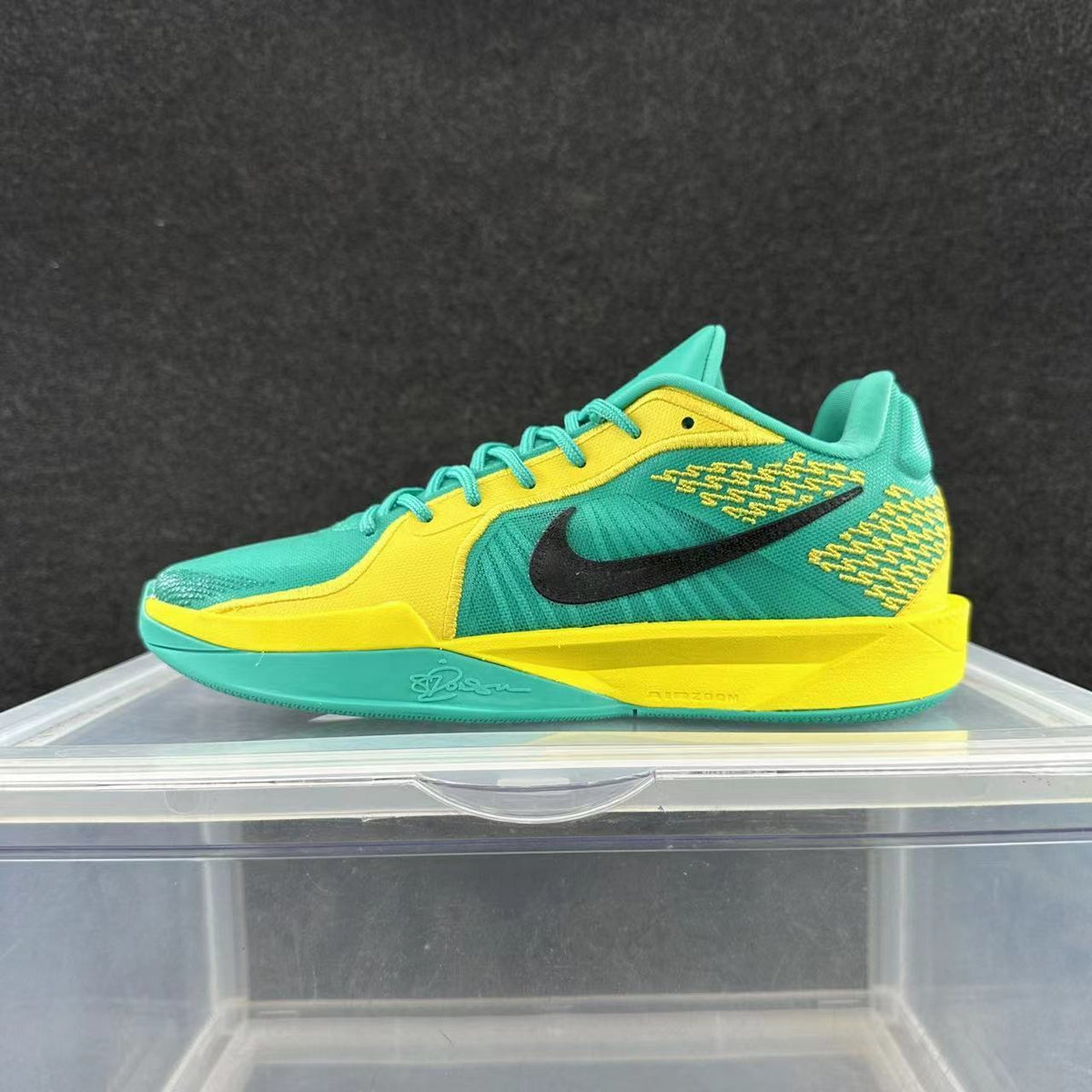 Side view of a turquoise and yellow Nike basketball shoe with a black Swoosh and contrasting sole.