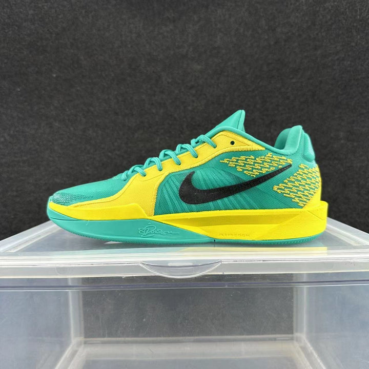 Side view of a turquoise and yellow Nike basketball shoe with a black Swoosh and contrasting sole.