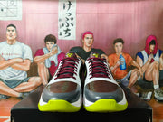 Front view of Nike basketball shoes showing dark red-and-black laces, dark toe panels, and bright yellow-green outsole accents.