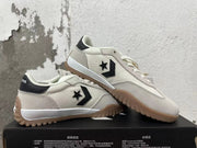 Pair of cream Converse low-top sneakers with black side logos and gum-colored outsoles