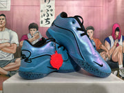 Pair of iridescent blue Nike basketball shoes shown at an angle, with black laces and a red charm
