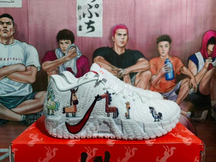 White Nike basketball sneakers with red Swoosh branding, illustrated side graphics, textured panels, and a red patterned shoe box.