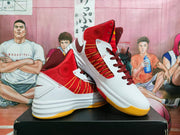 Angled view showing the red textile-like upper, white overlays, yellow accent lines, dark red laces, and layered white midsole.