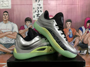 Angled view of the silver and black Jordan basketball sneakers displaying the side panels, black collars, and translucent pale green soles.