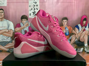Angled view of the pink Nike basketball sneakers highlighting the side branding, perforated upper details, and layered sole.