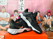 Angled view of two black Nike basketball sneakers displaying gold branding, perforated side panels, white midsoles, and black outsoles.