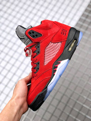 Close-up side view of a red and black Jordan Air Jordan 5 sneaker with grey tongue, mesh panel, and icy-blue outsole.
