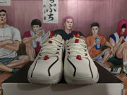 Front view of white Nike basketball sneakers with black trim, red accents, and perforated toe panels on a shoebox.