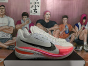 Side profile showing the white upper, black Swoosh, peach-pink forefoot accent, and layered sole.