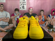 Front view of yellow Nike basketball sneakers with black tongue logos and perforated toe panels on a black box.
