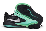 Black and green Nike Sabrina 4 shoe shown beside its outsole