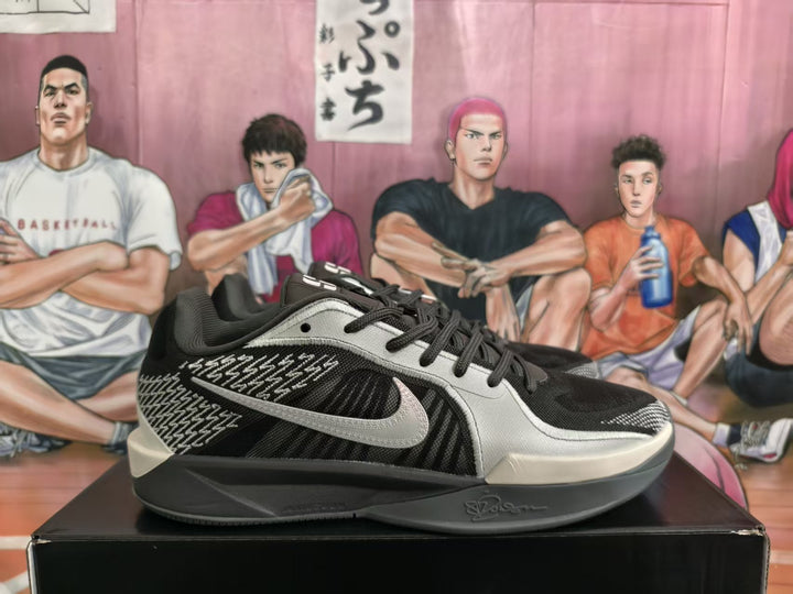 Side view of black and light-gray Nike basketball sneakers on a black box, showing the Swoosh and patterned side panel.