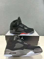Angled view showing the black upper, perforated side panel, red midsole detail, and translucent outsole