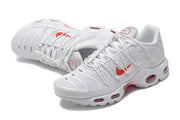 Angled view of a pair of white and red sneakers with mesh-look uppers and patterned soles.
