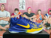 Side view of blue and yellow Nike Kobe basketball shoes on a black box