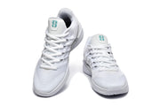 Pair of white low-top basketball shoes viewed from the front, with teal tongue logos and white laces