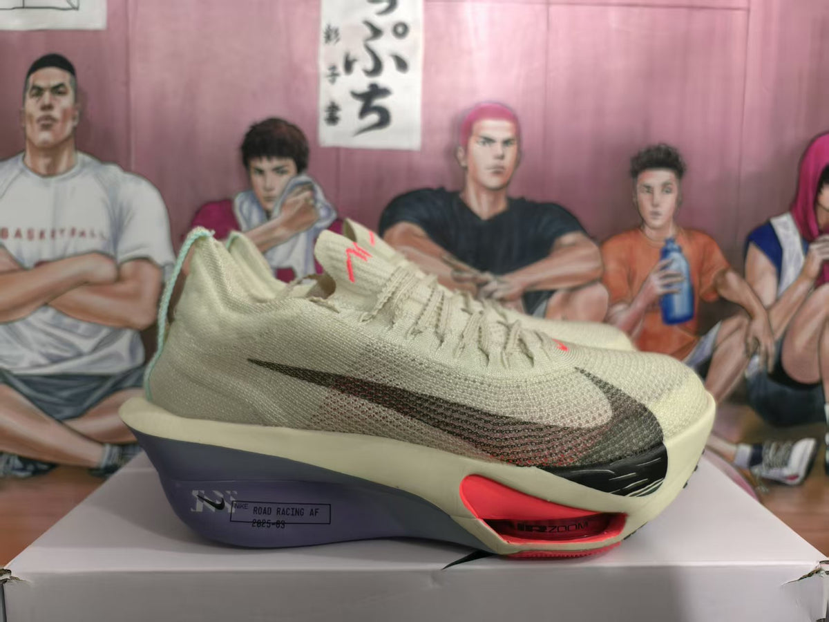 Side view of beige Nike sneakers with black side branding, red midsole accents, and visible ZoomX lettering.