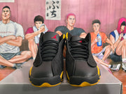 Front view of black high-top sneakers with yellow accents and red tongue logos
