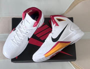 Pair of white high-top shoes arranged on a black and red shoe box.