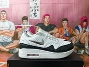 Side profile of a white and black Nike sneaker with perforated panels, metallic-look Swoosh and visible midsole cushioning.