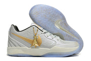 Light gray Nike Ja 2 shoe with gold details beside the outsole and a hanging gold charm