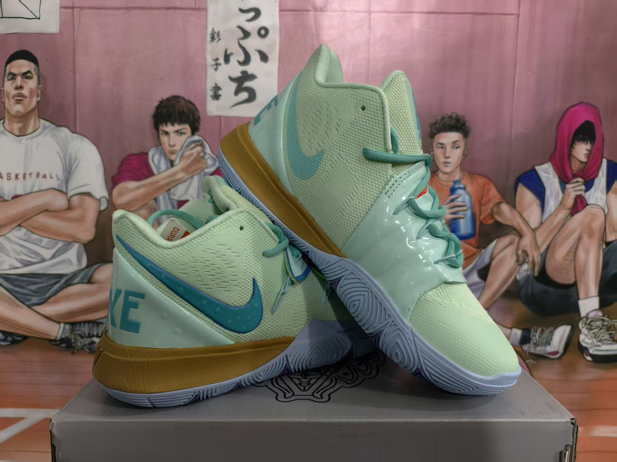Pair of mint green Nike basketball sneakers with blue accents and gold-toned midsoles displayed on a box.