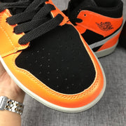 Detail of the black perforated toe box, laces and orange overlay.