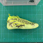 Lime-green sneaker with black patterned panels shown from above on a measuring mat