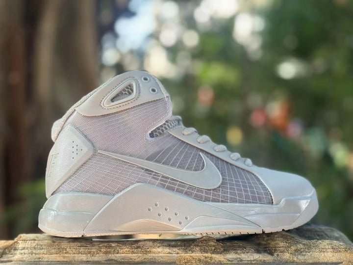 Side view of gray and off-white Nike high-top basketball sneakers with a visible Swoosh and padded collar.