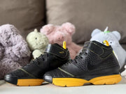 Pair of black and yellow sneakers displayed from a side angle.