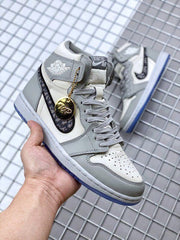 Angled front-side view showing the perforated toe box, gray laces, patterned Swoosh, and charm.