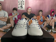 Front view of the white and blue Nike basketball sneakers showing the white mesh-like uppers, white laces and black outsoles.