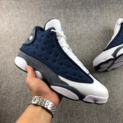 Side view of the navy, white, and charcoal Air Jordan 13 Flint sneaker.