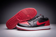 Black and red low-top Jordan sneakers showing the red patterned outsole and side profile.