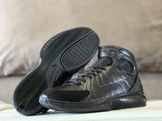 Black high-top shoe shown beside its outsole, with chevron and geometric tread patterns.